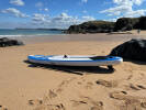 Enigma 11ft paddleboard laying on a sandy beach